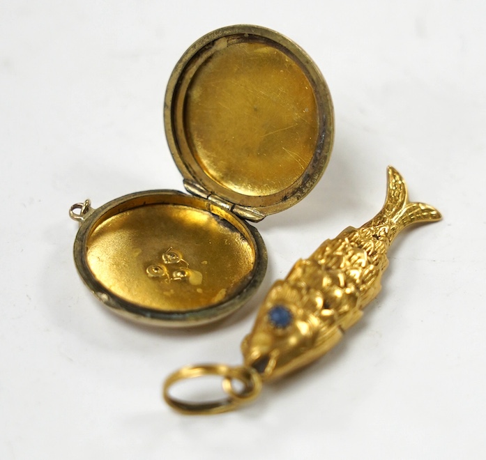 An Italian 750 yellow metal and two stone blue cabochon set articulated gold fish pendant, overall 46mm and a yellow metal and split pearl set circular locket. Condition - poor to fair